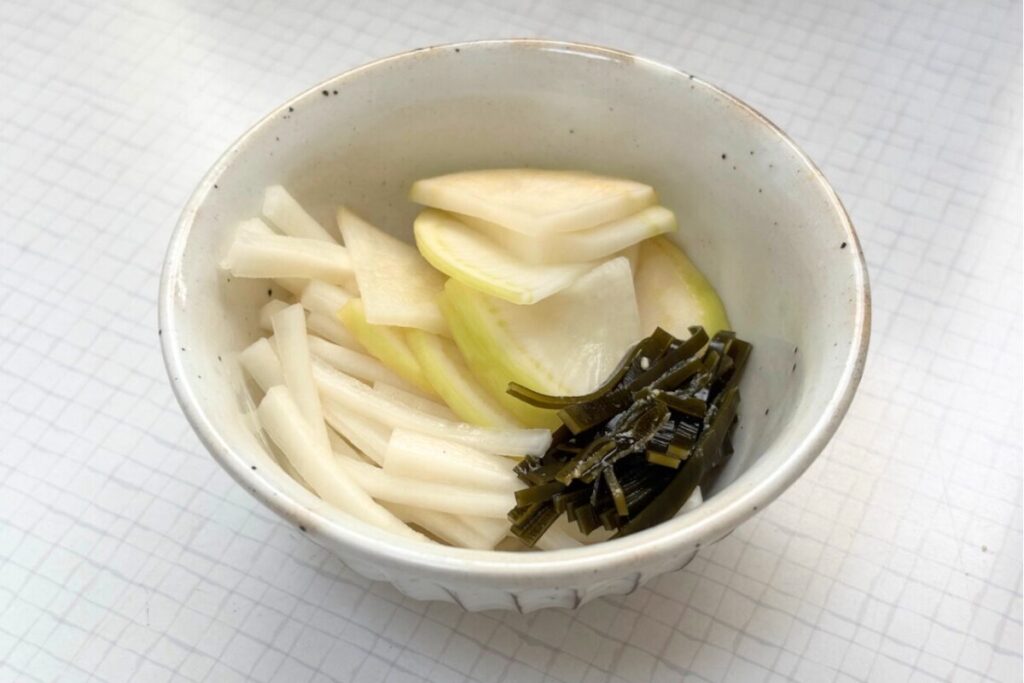 白い器に盛り付けられた大根のぬか漬け。一緒に漬けた昆布も添えられている。