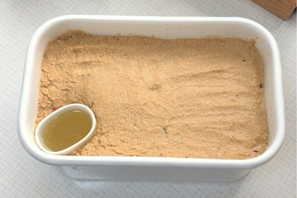 白い琺瑯容器に入ったぬか床の様子。角に水取り器が入っている。